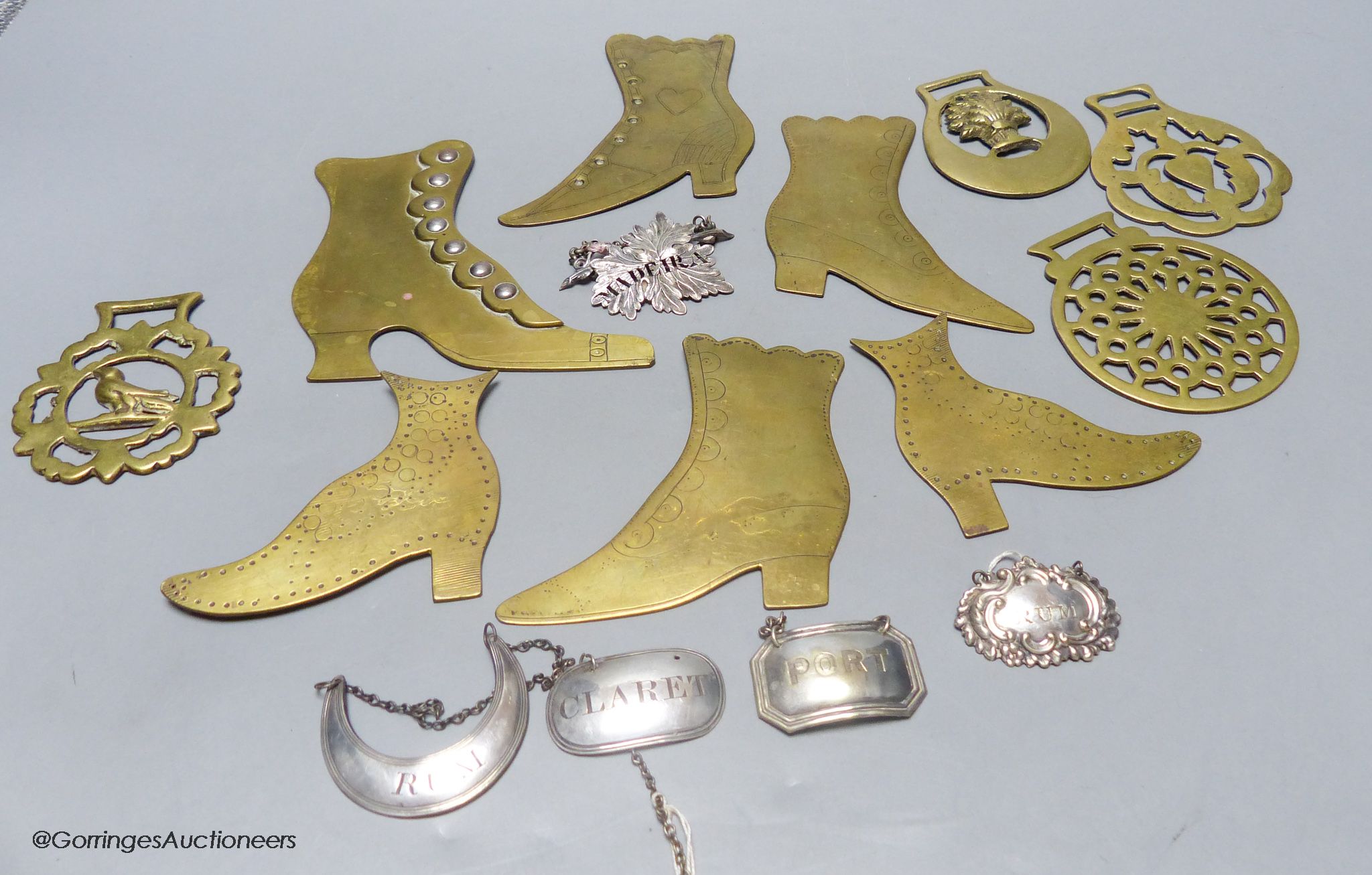 A group of plated wine labels and brass model shoes